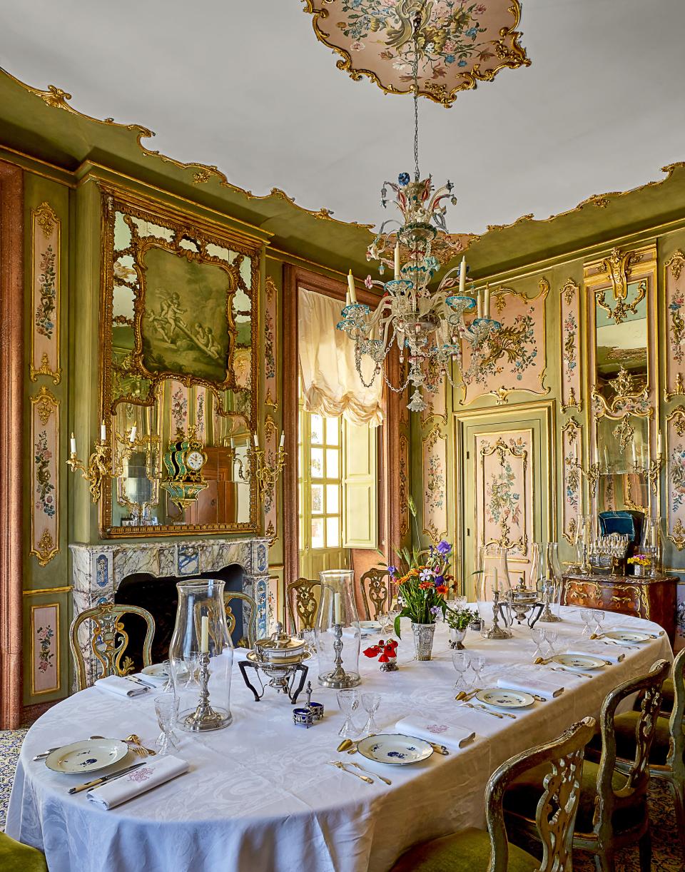 An 18th-century murano chandelier hangs in the gilded dining room. On table, Chantilly porcelain; antique Italian Rococo chairs.