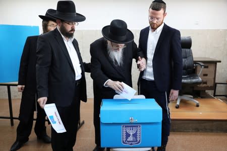 Ultra-Orthodox Jewish men help an elderly man cast his ballot as Israelis vote in a parliamentary election, at a polling station in Jerusalem's Mea Shearim neighbourhood