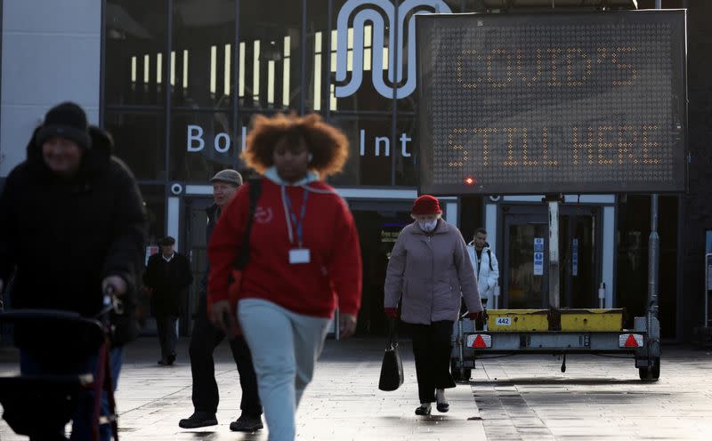 People walk past a health information board, amid the coronavirus disease (COVID-19) outbreak in Bolton