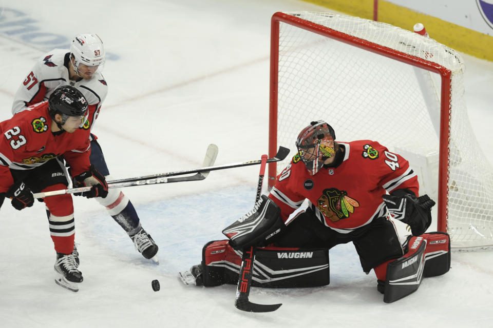 Chicago Blackhawks goalie Arvid Soderblom (40) makes a save while teammate Philipp Kurashev (23) battles Washington Capitals' Trevor van Riemsdyk (57) during the first period of an NHL hockey game Sunday, Dec. 10, 2023, in Chicago. (AP Photo/Paul Beaty)