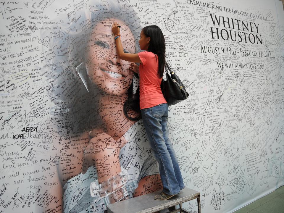 Whitney Houston, woman signs a giant mural with a portrait of her idol displayed at a mall in Manila on February 17, 2012, as part of the mall's tribute to the pop legend