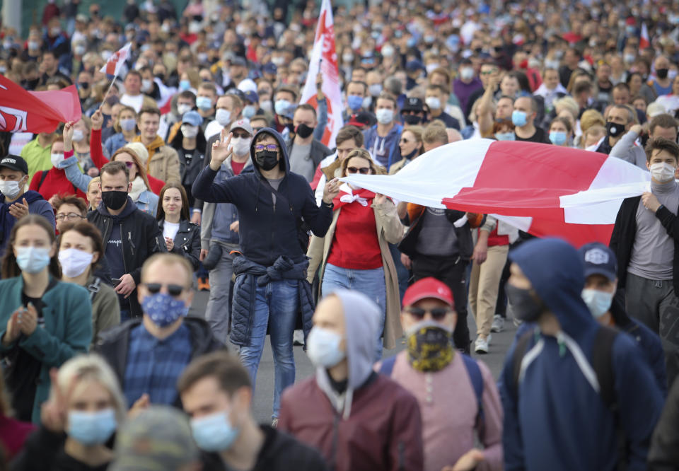 People with old Belarusian national flags march during an opposition rally to protest the official presidential election results in Minsk, Belarus, Sunday, Oct. 4, 2020. Hundreds of thousands of Belarusians have been protesting since the Aug. 9 presidential election. (AP Photo)