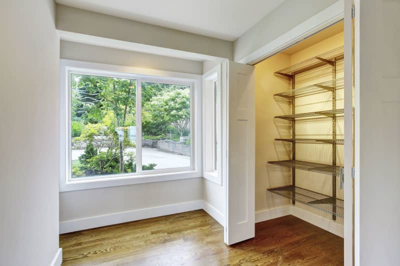 Hallway interior with hardwood floor and opened doors to walk-in closet with shelves. Northwest, USA