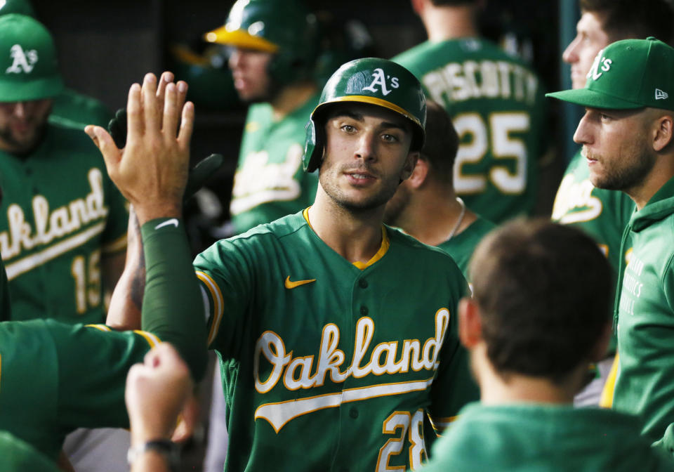 Oakland Athletics' Matt Olson is greeted in the dugout after hitting a solo home run against the Texas Rangers during the fourth inning of a baseball game in Arlington, Texas, Sunday, July 11, 2021. (AP Photo/Ray Carlin)
