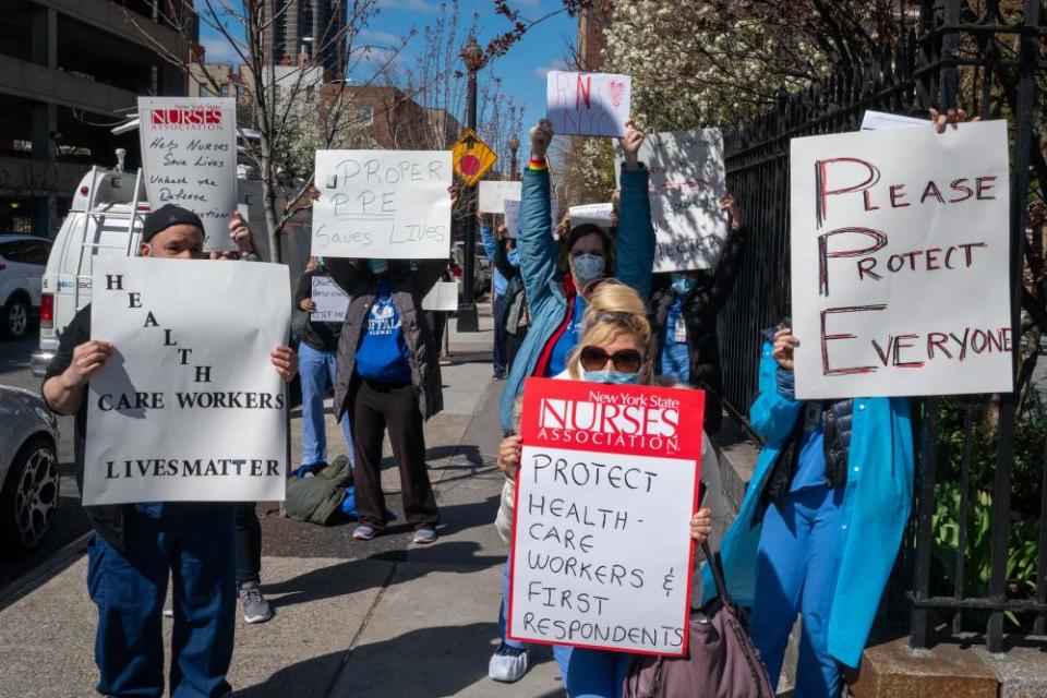 Nurses hold signs during a demonstration for increased personal protection equipment outside Montefiore Hospital in the Bronx borough of New York, U.S., on Thursday, April 2, 2020. Health-care workers and others essential to the Covid-19 fight say they’re increasingly frustrated that they’re being sent into a deadly battle without the protective gear they need for themselves and their patients.