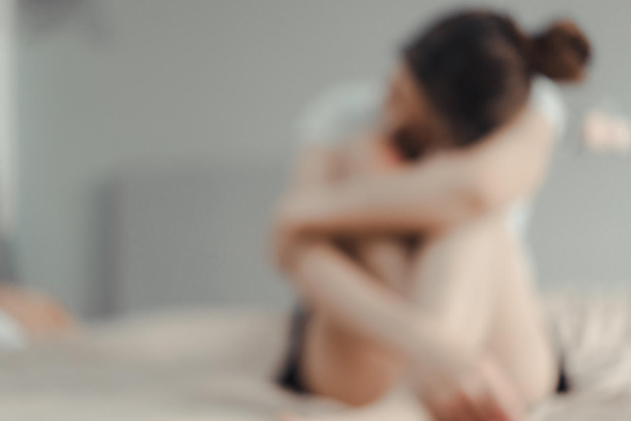 Defocused Image Of Sad Woman Sitting On Bed At Home