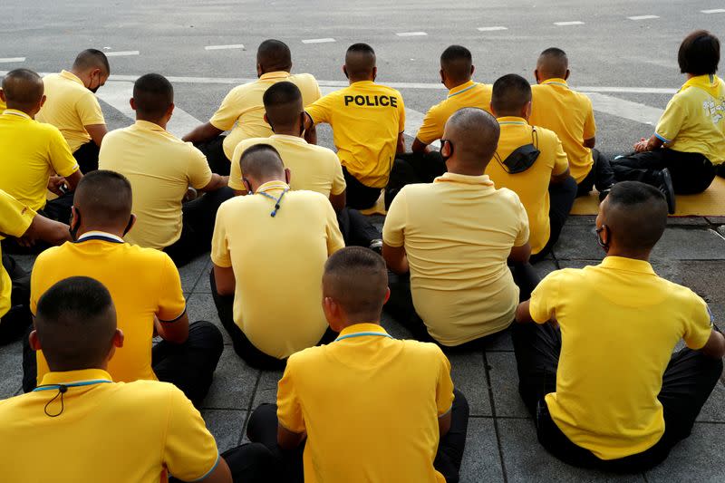 FILE PHOTO: Police officers sit on the ground after the motorcade carrying Thailand's King Maha Vajiralongkorn and Queen Suthida drove past in Bangkok