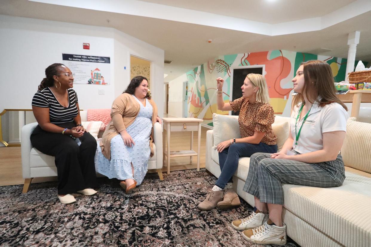 Executive Director Julie Wade, second from right, talks with the team at Tharros Place.