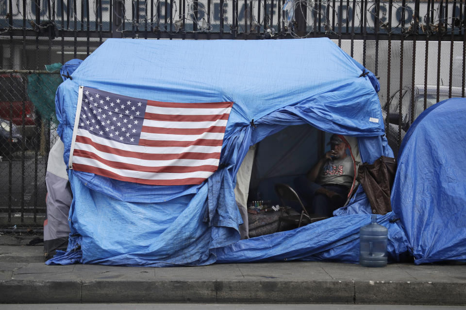 FILE - In this March 20, 2020, file photos, a man smokes inside a tent on skid row in Los Angeles. The 9th U.S. Court of Appeals on Thursday, Sept. 23, 2021, overturned a federal judge’s sweeping order that required the city and county of Los Angeles to quickly find shelter for all homeless people living on downtown’s Skid Row. (AP Photo/Marcio Jose Sanchez, File)