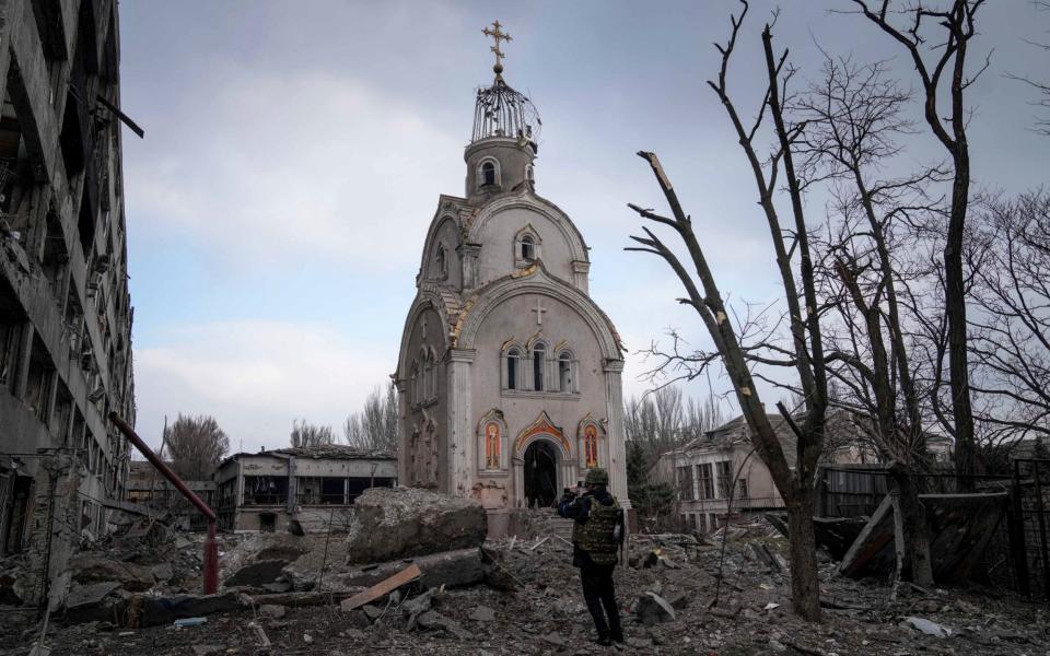 A Ukrainian serviceman takes a photograph of a damaged church after shelling in a residential district in Mariupol, Ukraine, Thursday, March 10, 2022. - Evgeniy Maloletka/AP