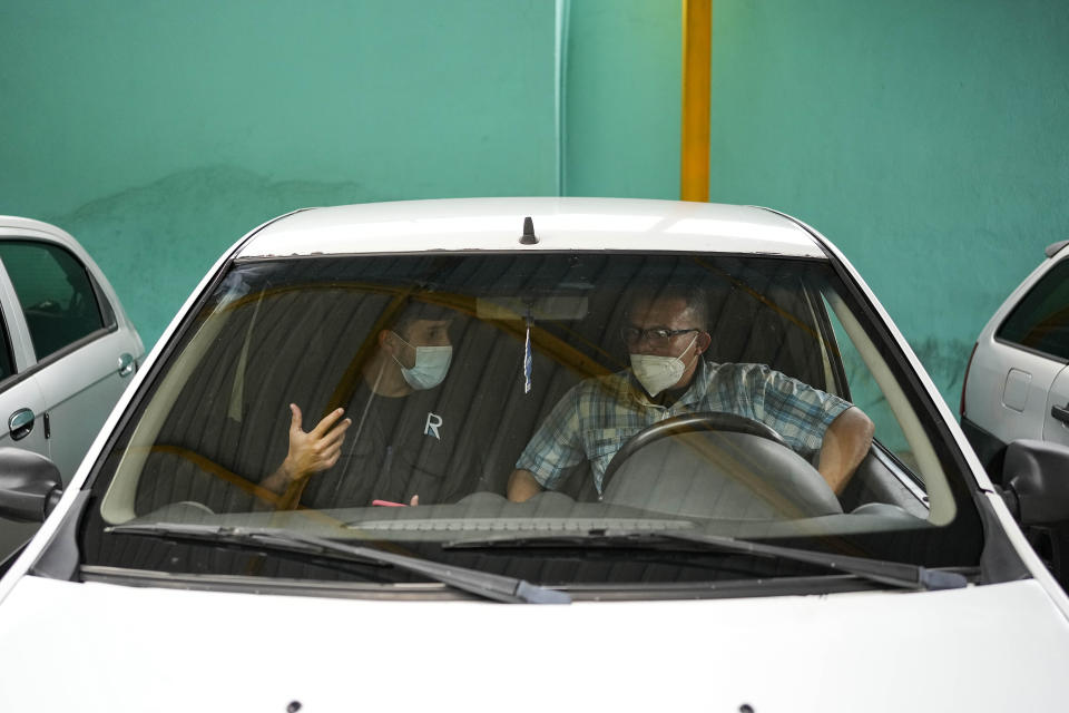 An employee gives tips to a driver to move on to the next phase of recruitment at Ridery HQ in Caracas, Venezuela, Wednesday, May 4, 2022. Ridery is one of at least three Venezuelan ride-sharing apps that launched during the pandemic. (AP Photo/Matias Delacroix)