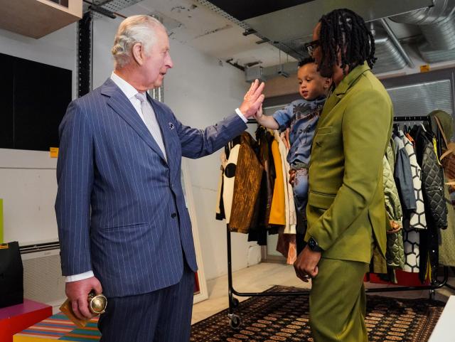 Britain&#39;s King Charles III gives a hi-five to Idris, 2, the son of founder and creative director of LABRUM London Foday Dumbuya (R) and winner of the Queen Elizabeth II Award for British Design, during a special industry showcase event hosted by the British Fashion Council (BFC) at 180 Studios, in London, on May 18, 2023.