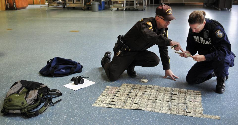 Somerset County Sheriff's Office Cpl. Gene Cole, left, helps Maine State Police Trooper Diane Vance inventory money recovered from Christopher Knight Tuesday April 9, 2013 at the Pine Tree Camp in Rome. Knight, a hermit who lived in the woods since April 1986, was apprehended when he broke into the camp, police claim. He was captured carrying a knapsack and bag of tools. Many of bills date from the 1980s and 1990s, Vance said, and were never circulated by Knight.  (Photo by Andy Molloy/Portland Press Herald via Getty Images)