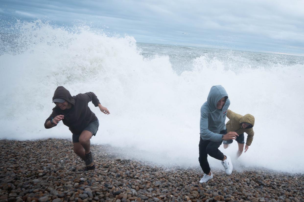 People play amongst the waves on Chiswell Beach in Dorset, Wednesday 2 August (PA)