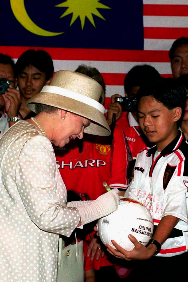 Queen Elizabeth II signs a football