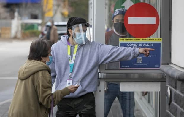 A health care worker directs a Toronto resident to a COVID-19 mass vaccination clinic at the East York Town Centre mall in the city's Thorncliffe Park neighbourhood on March 24, 2021.