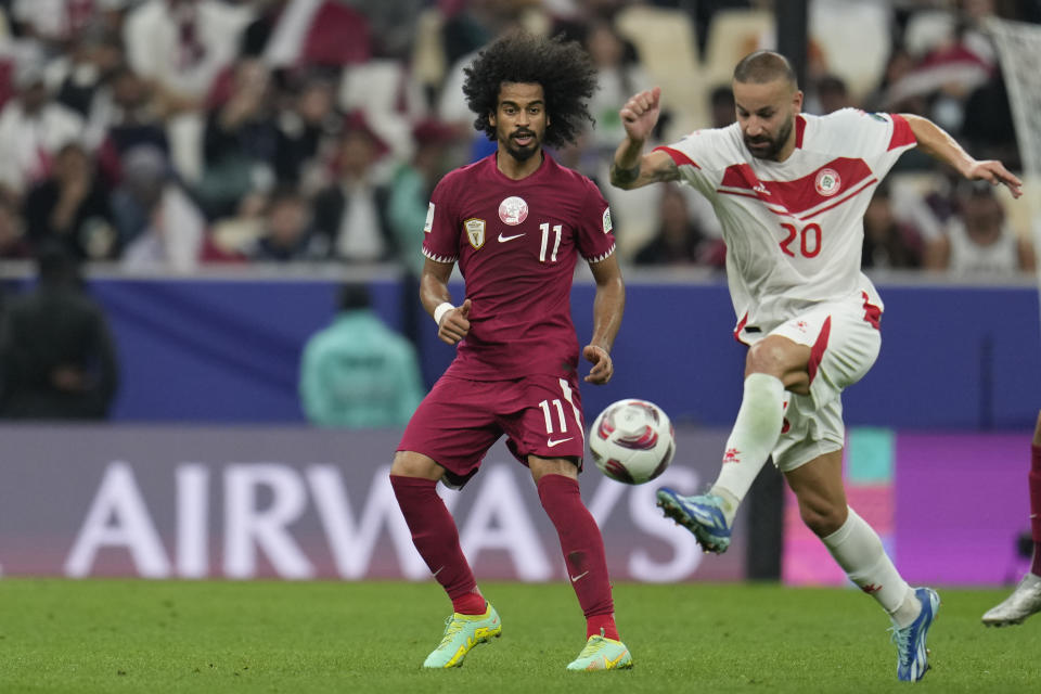 Qatar's Akram Afif, left, is challenged by Lebanon's Ali Tneich during the Asian Cup Group A soccer match between Qatar and Lebanon at the Lusail Stadium in Lusail, Qatar, Friday, Jan. 12, 2024. (AP Photo/Aijaz Rahi)