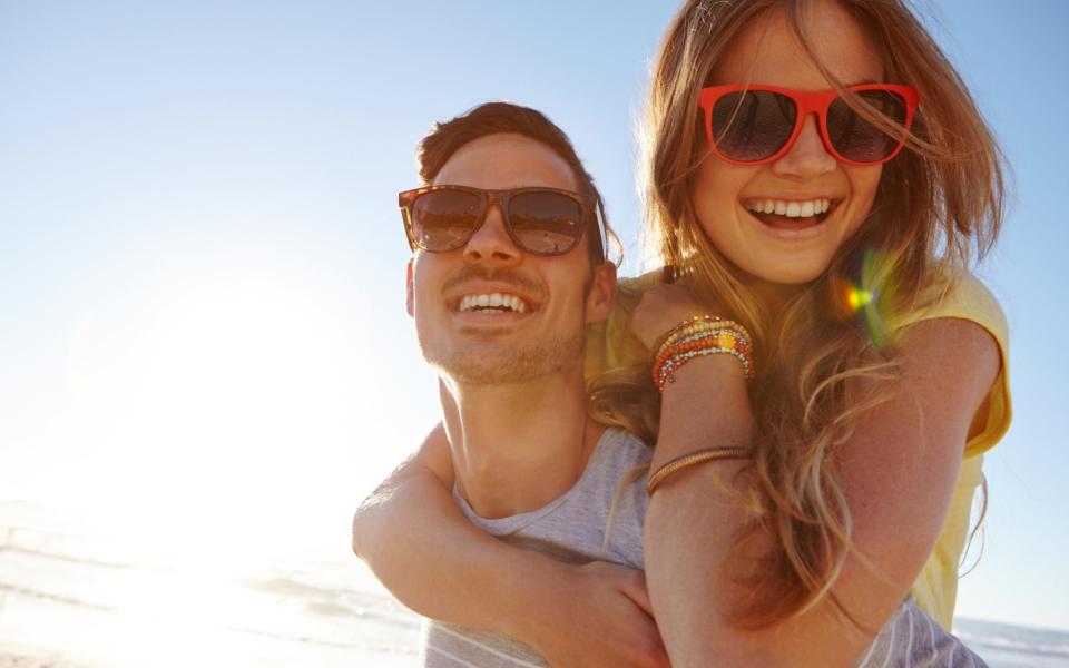 handsome young man giving his girlfriend a piggyback at the beach - Credit: e+