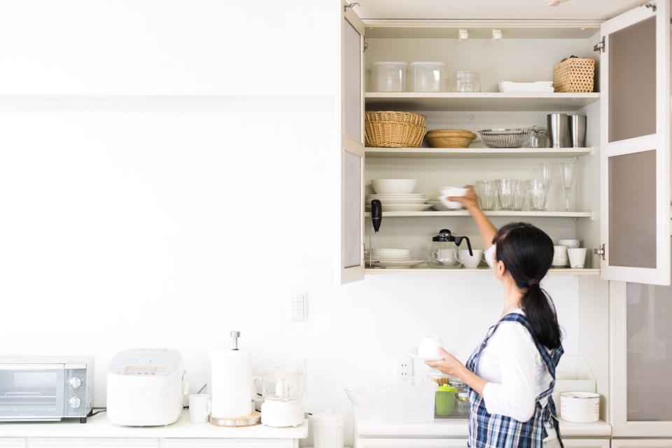 woman stacking bowls and plates in cupboard