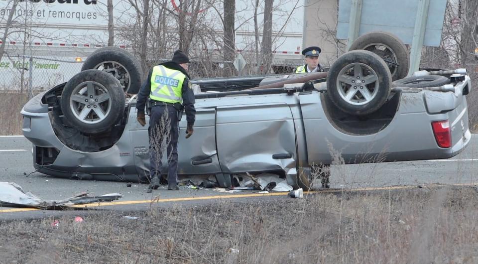 Police examine a flipped-over truck by the westbound Queen Elizabeth Way ramp to Brant Street in Burlington, Ont. Monday.  (Andrew Collins - image credit)