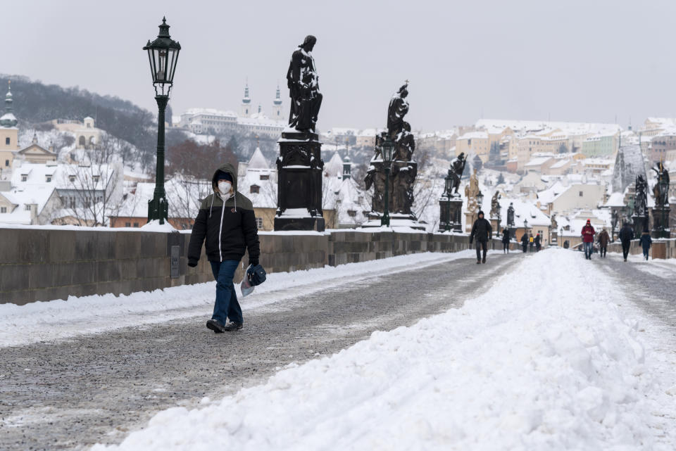 A woman wearing a facemask as a preventive measure against the spread of coronavirus, walks on the iconic Charles Bridge. Heavy snowfall across the Czech Republic has disrupted rail, road and public transport. (Photo by Tomas Tkacik / SOPA Images/Sipa USA)