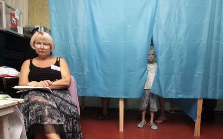 A boy looks out of a voting booth at a polling station in the Crimean port of Sevastopol, September 14, 2014. REUTERS/Stringer
