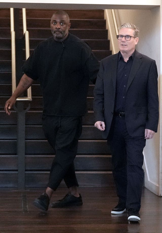 Idris Elba and Sir Keir Starmer walking together in front of a staircase 