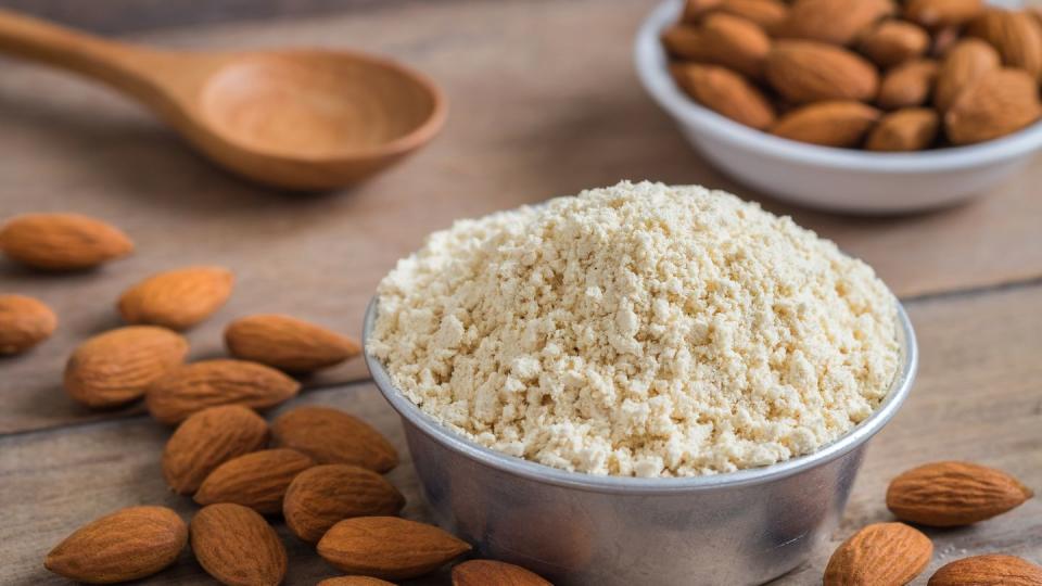 almond flour in bowl and almonds on wooden table