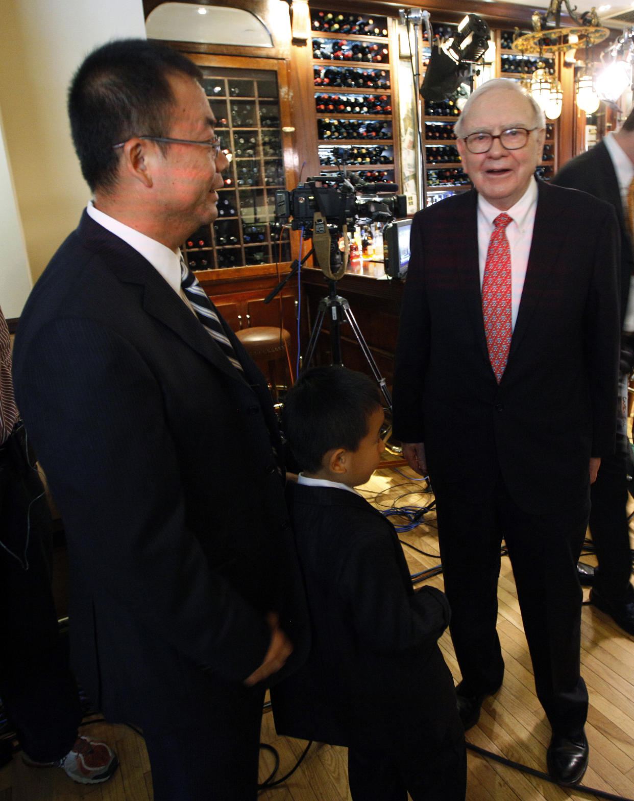 Hedge fund manager Zhao Danyang (L) and his son Zhao Ziyang (age 5 1/2) stand with billionaire investor Warren Buffett after placing the winning bid in a charity auction for lunch with Buffett in New York, June 24, 2009. Buffett, the Omaha, Nebraska-based chief executive officer of Berkshire Hathaway, handed his wallet to the younger Zhao and then whispered him a stock tip as they passed by photographers after completing television interviews at New York's famous steak house, Smith&Wollensky.     REUTERS/Chip East   (UNITED STATES BUSINESS SOCIETY)