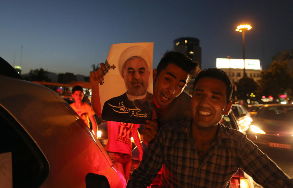 Iranians celebrate the victory of moderate presidential candidate Hassan Rouhani (portrait) in the presidential elections at Vanak square in northern Tehran on June 15, 2013. Iranian Interior Minister Mohammad Mostafa Najjar said Rouhani won outright with 18.6 million votes, or 50.68 percent. (ATTA KENARE/AFP/Getty Images)