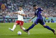 Argentina's Enzo Fernandez, right, kicks a the ball as Poland's Matty Cash defends during the World Cup group C soccer match between Poland and Argentina at the Stadium 974 in Doha, Qatar, Wednesday, Nov. 30, 2022. (AP Photo/Darko Bandic)