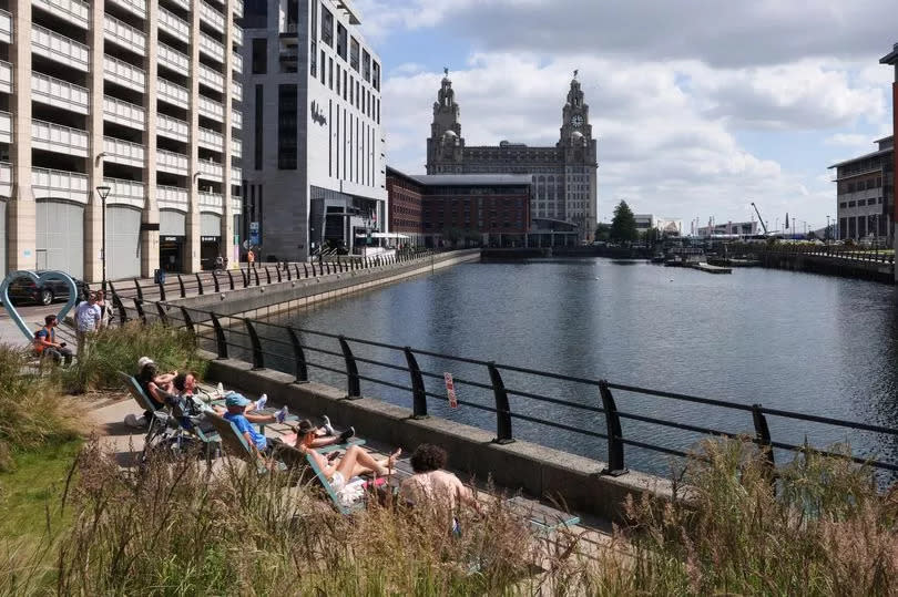 People sunbathe by Princes Dock in Liverpool today