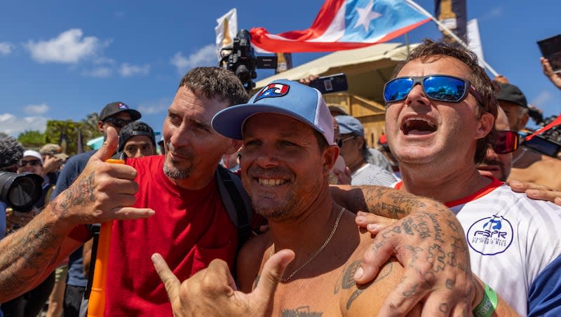 Brian Toth from Puerto Rico, center, poses for a photo with fans at the ISA World Surfing Games, a qualifier for the Paris 2024 Olympic Games, on La Marginal beach in Arecibo, Puerto Rico, Thursday, Feb. 29, 2024.