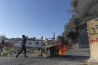 Palestinian protesters burn tires and use slingshots during clashes with Israeli soldiers at the entrance the Jewish settlement of Beit El, background, near the West Bank city of Ramallah, Tuesday, June. 15, 2021. (AP Photo/Nasser Nasser)