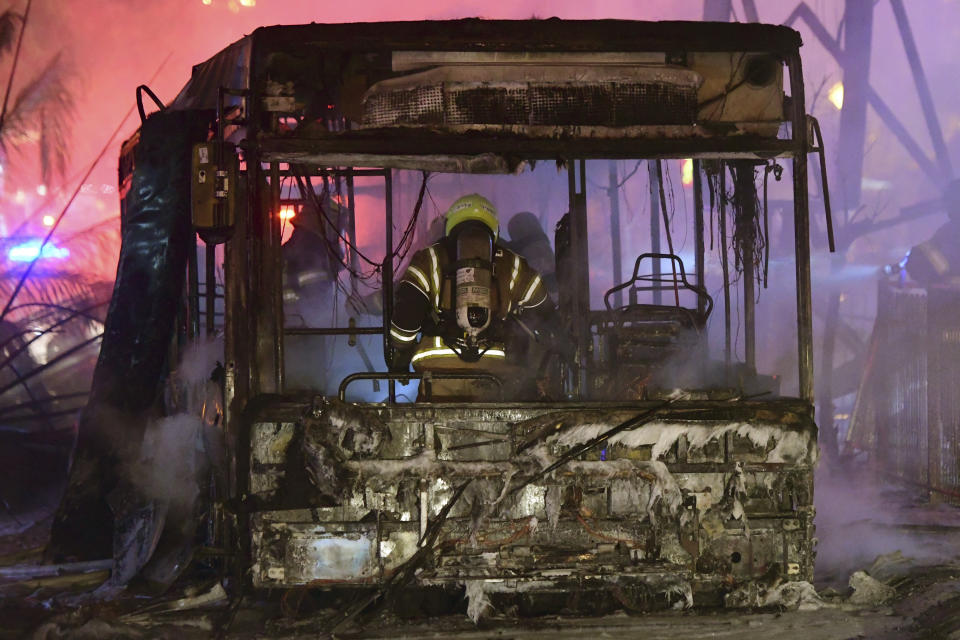 An Israeli firefighter extinguishes a burning bus after it was hit by a rocket fired from the Gaza Strip, at the central Israeli town of Holon, near Tel Aviv, Tuesday, May 11, 2021. (AP Photo/Avshalom Sassoni)