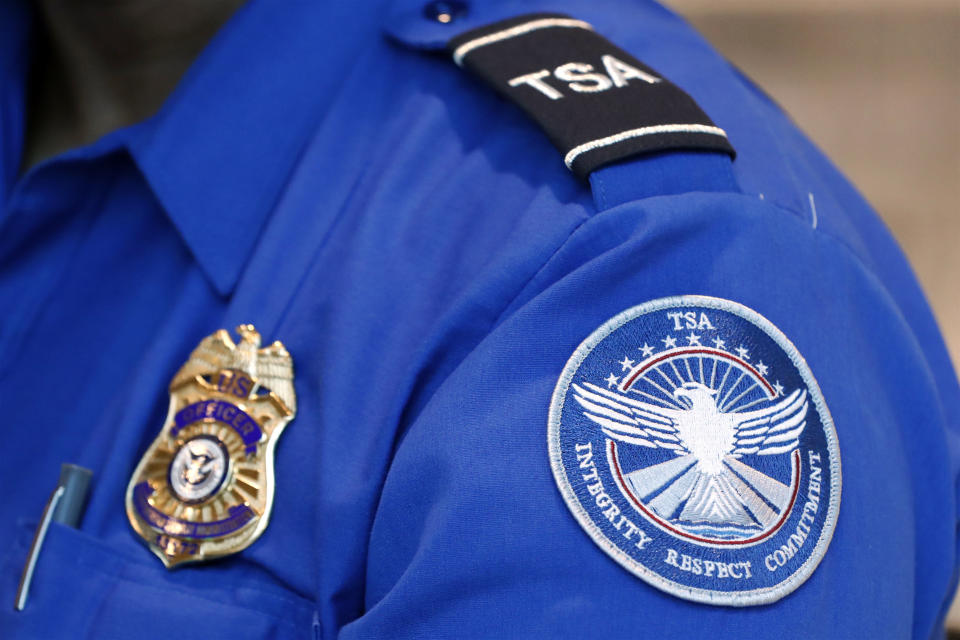 FILE - In this June 24, 2020, file photo, a Transportation Security Administration officer works at Love Field in Dallas. President Donald Trump has repeatedly credited his February ban on travelers from mainland China as his signature move against the advance of the coronavirus pandemic -- a “strong wall” that allowed only U.S. citizens inside, he boasted in May. But Trump’s wall was more like a sieve. Exempted were thousands of residents of the Chinese territories of Hong Kong and Macau. (AP Photo/Tony Gutierrez, File)