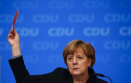 German Chancellor and leader of the Christian Democratic Union (CDU) Angela Merkel holds up her voting card during a vote on a resolution about refugees at the CDU party congress in Karlsruhe, Germany December 14, 2015. REUTERS/Kai Pfaffenbach