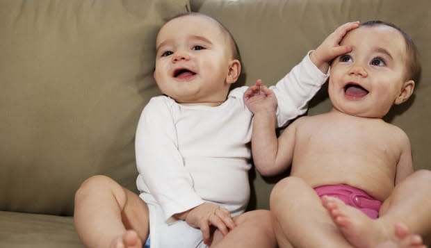 Twin brother and sister on a couch smiling