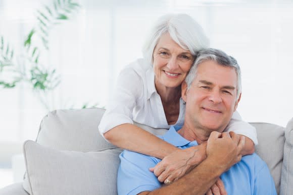 Older couple smiling on a couch.