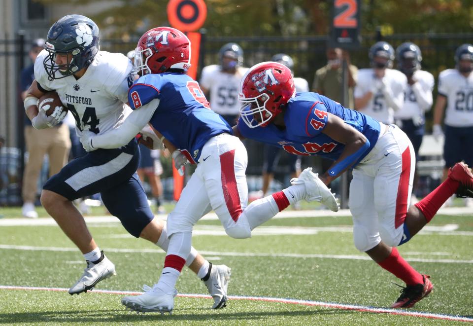 Pittsford's Nathan Rodi rushes down inside the ten yard line, dragging Monroe's Mark Mathis, center, and Divine Thomas, right, with him during their Section V season opening game Saturday, September 4, 2021 at James Monroe High School in Rochester. 