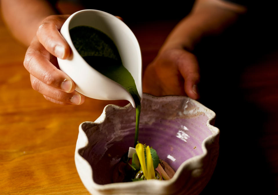 Chef Aaron Verzosa pours a wild nettle laing sauce to complete the Anak ni Bet, his version of pinakbet, at Filipino American restaurant Archipelago, Wednesday, May 24, 2023, in Seattle. Verzosa is nominated for a 2023 James Beard Award in the Best Chef: Northwest and Pacific category. (AP Photo/Lindsey Wasson)