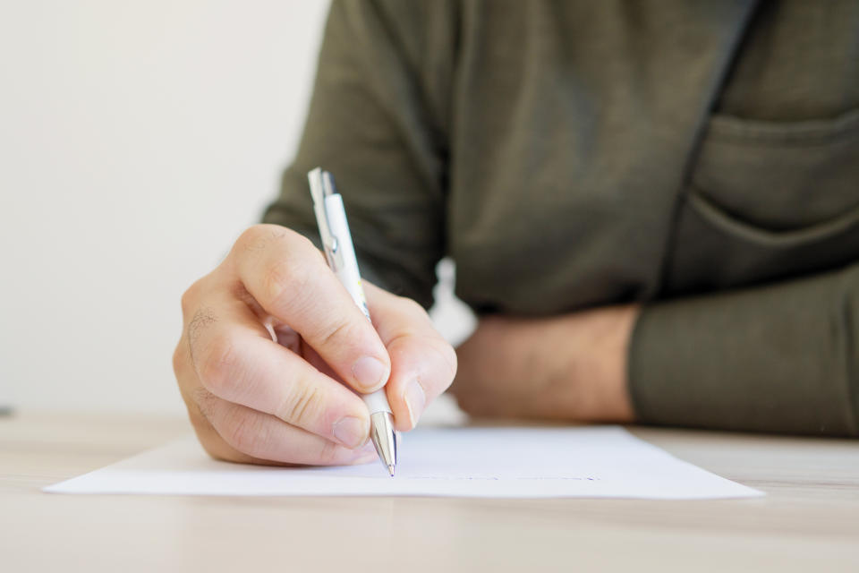 Close-up of a person's hand writing a letter, possibly relating to romantic correspondence