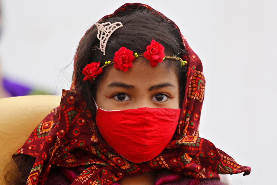 A Christian girl wearing a face mask as a precaution against the coronavirus attends the Christmas mass at a church in Ahmedabad, India, Friday, Dec. 25, 2020. (AP Photo/Ajit Solanki)