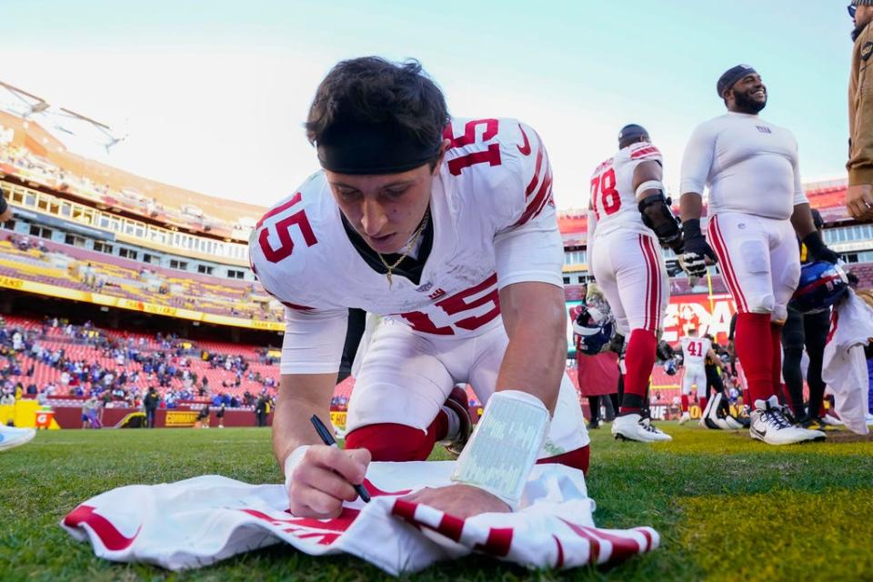 New York Giants quarterback Tommy DeVito (15) signs a team jersey following the end of an NFL football game against the Washington Commanders, Sunday, Nov. 19, 2023, in Landover, Md. Giants won 31-19. (AP Photo/Andrew Harnik)