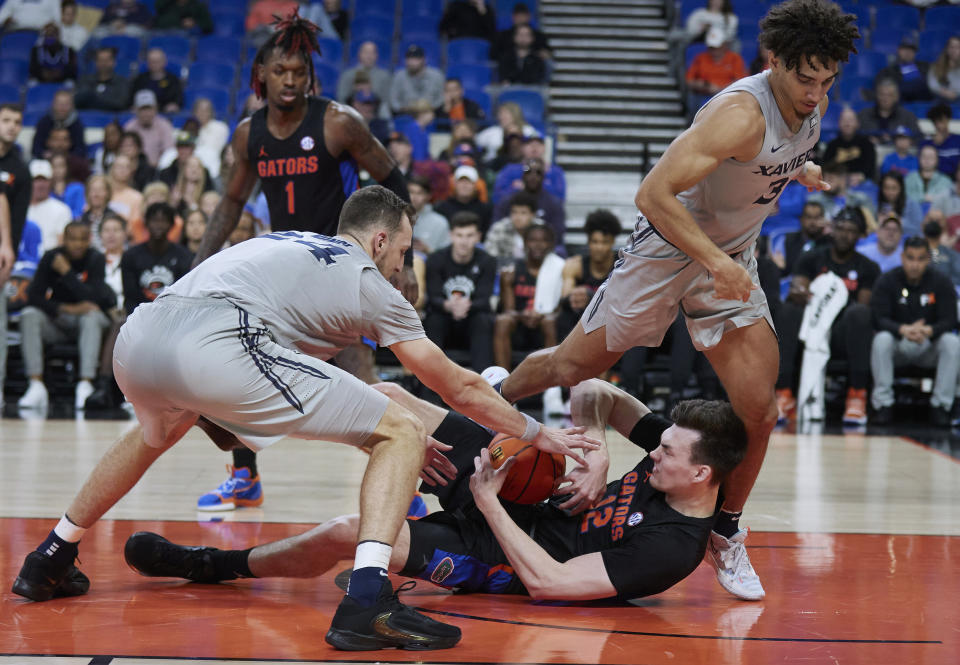 Florida forward Colin Castleton (12) and Xavier forward Jack Nunge, left, reach for the ball during the first half of an NCAA college basketball game in the Phil Knight Legacy tournament in Portland, Ore., Thursday, Nov. 24, 2022. Xavier guard Colby Jones steps over Castleton. (AP Photo/Craig Mitchelldyer)