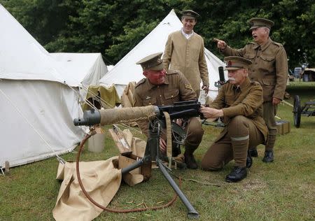 Police Community Support Officer (PCSO) Peter Austridge (L), portraying a Corporal in the 4th Battalion Royal Fusilier Territorial Army, recreates the camp life of a First World War soldier with other re-enactors Steve Neville (2nd L) Andrew Morgan (2nd R) and Phil Curtis (R) at the Colchester Military Tournament in Colchester, eastern England July 6, 2014. REUTERS/Luke MacGregor