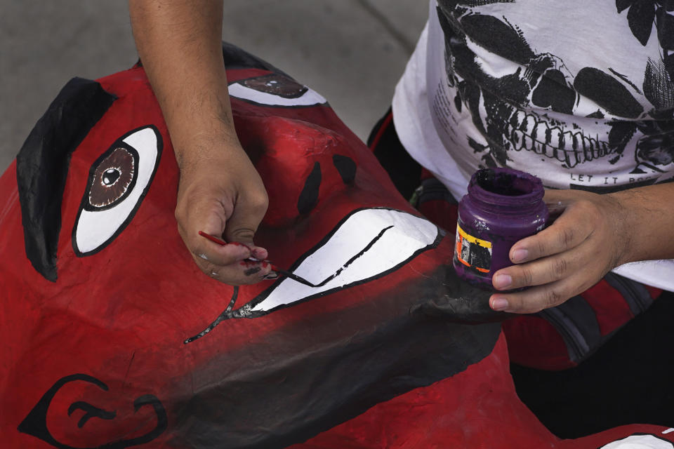 An artisan paints a cardboard figure of "Judas" for the upcoming "Burning of Judas," celebration, at the Santa Maria La Ribera Cultural Center, in Mexico City, Wednesday, April 5, 2023. During this popular activity on the sidelines of the Holy Week celebrations of the Catholic Church, people gather in neighborhoods on Holy Saturday across the country to burn cardboard symbolic embodiments of evil. (AP Photo/Marco Ugarte)