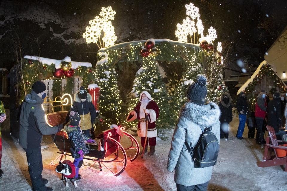 Santa Claus meets young people in old historic Petit Champlain District in Quebec City, Sunday, Dec. 20, 2020. (Jacques Boissinot/The Canadian Press via AP)