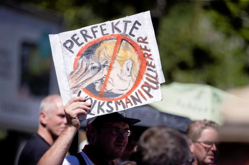 Ein Teilnehmer hält ein Schild mit einer Merkel-Karikatur und der Aufschrift "Perfekte Volksmanipulation" auf der Demonstration gegen die Corona-Beschränkungen. Zu der Demonstration gegen die Corona-Maßnahmen hat die Initiative "Querdenken 711" aufgerufen.<span class="copyright">Christoph Soeder / dpa</span>