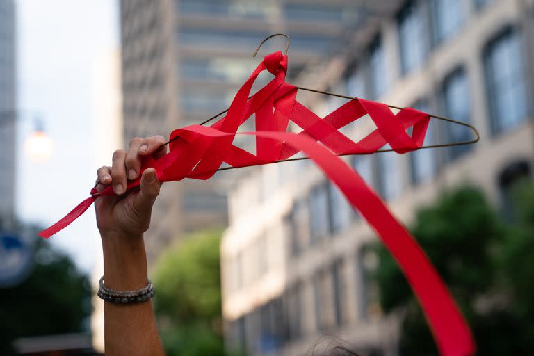 Una mujer sostiene una percha envuelta en un lazo rojo frente al Tribunal de Apelaciones de Estados Unidos para el Undécimo Circuito durante una protesta contra el fallo del Tribunal Supremo de anular el histórico caso Roe v Wade